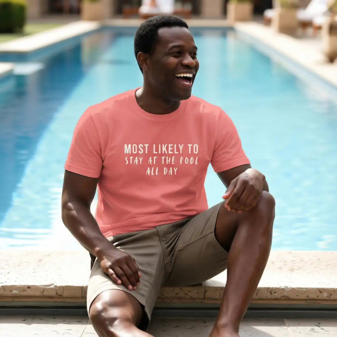 Coral-colored cotton t-shirt with white text reading ’most likely to stay at the pool all day’ across the chest.