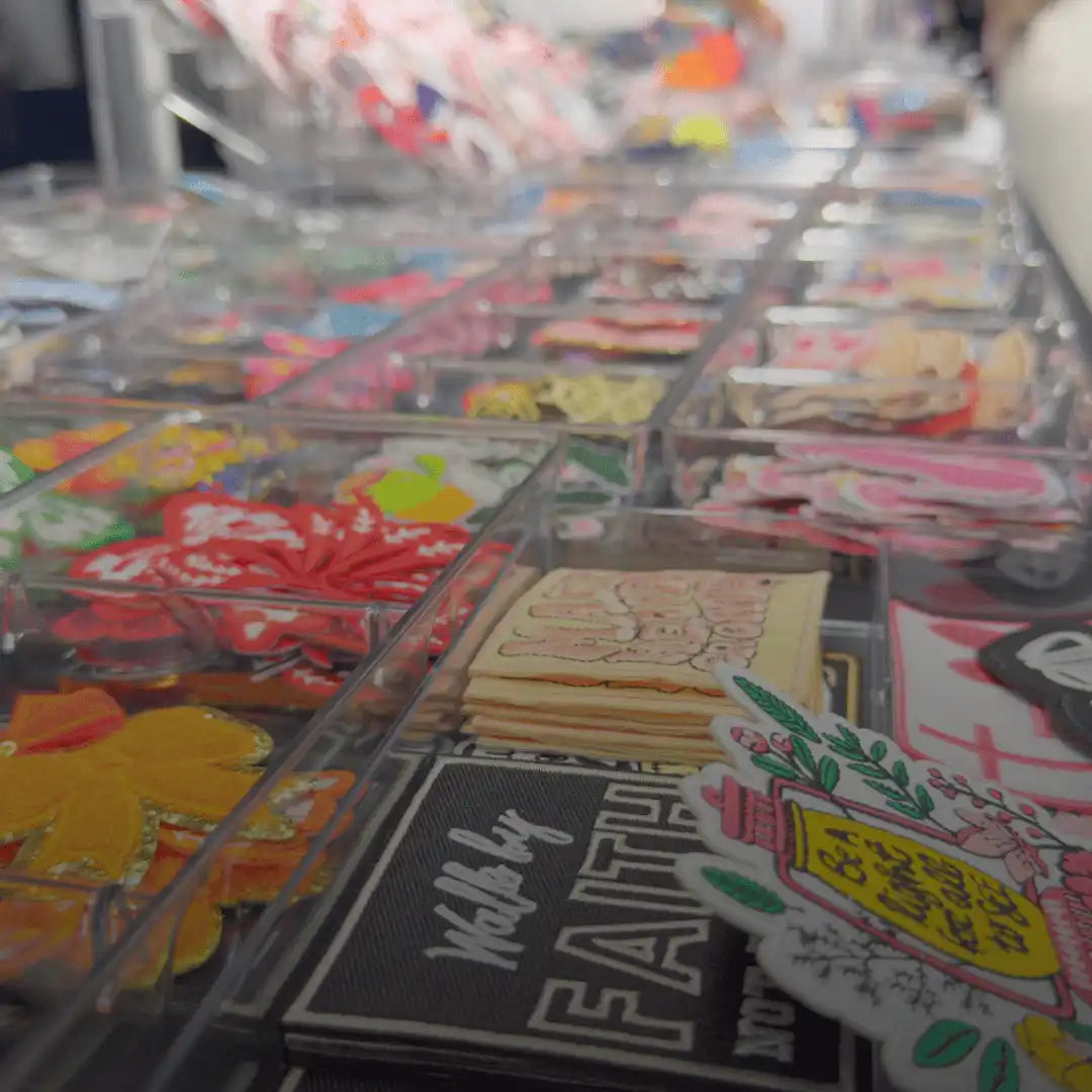 Assorted colorful craft supplies and decorative patches in clear organizers.